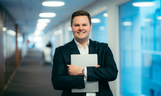 Gunnar Høivik står med PC-en i et kontorlandskap hos DNB. 